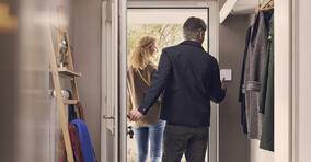 Paar verlässt Zuhause. Mann schaltet Alarmanlage an.